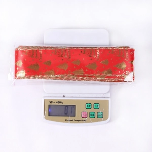 Gros plan du ruban de Noël rouge et or de 6,3 cm pesant 81 g sur une balance de cuisine