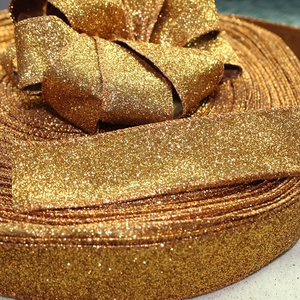 Close-up of sparkling gold glitter ribbon with festive bow showing fine texture