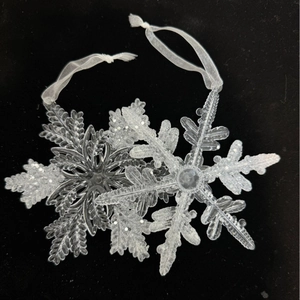 Detail view of clear acrylic and white glitter snowflake ornaments with ribbon ties