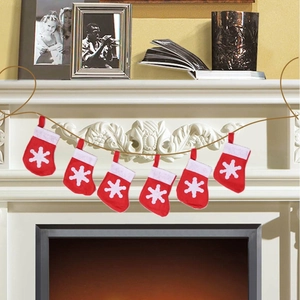 Close-up of red Christmas stocking banner with white snowflakes hanging on a fireplace
