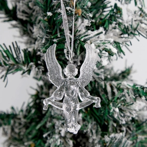 Clear acrylic Christmas angel ornament with silver string hanging on a snowy tree branch
