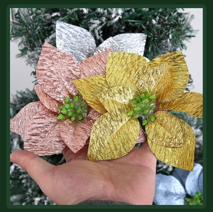 Detail of glittered artificial Christmas flowers in gold and silver on a tree branch