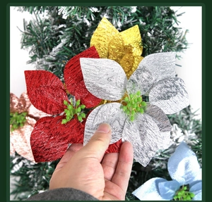Close-up of sparkling fabric poinsettia flowers on a Christmas tree with hand holding