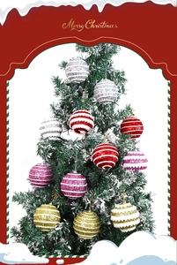 Close-up of glitter striped Christmas balls hanging on snowy tree branches