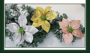 Detailed view of silver, gold and rose gold artificial Christmas poinsettias on pine needles