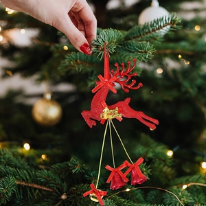 Detailed view of a red reindeer Christmas tree ornament with golden Merry Christmas text