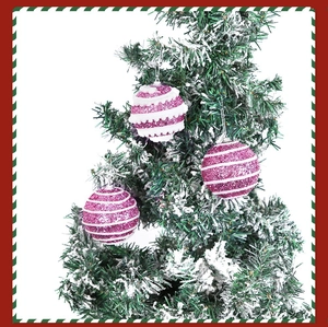 Detailed view of pink and white striped sequin Christmas balls hanging on a snowy tree branch