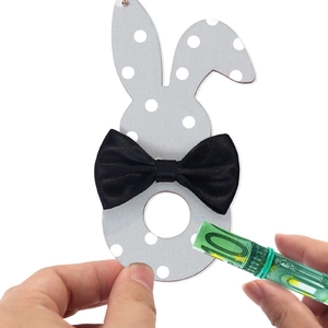 Detail of wooden Easter bunny money holder with black bow and 100 euro cash gift insert