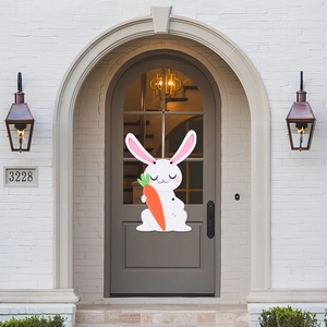 Close-up of Easter white bunny door hanger holding a carrot on an arched grey entrance