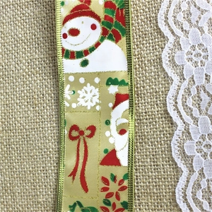 Close-up of golden Christmas ribbon with snowman patterns on a rustic burlap background