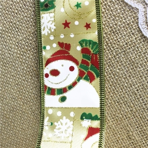 Close-up of gold glitter Christmas ribbon featuring snowman patterns on burlap background