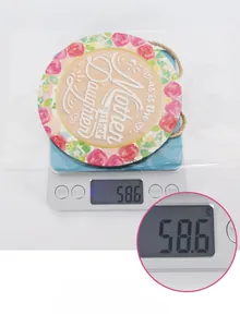 Weight display of a round wooden Mother's Day plaque with pink roses and twine