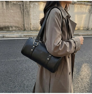 Sac cylindre classique en cuir huilé noir porté par un mannequin en style urbain décontracté