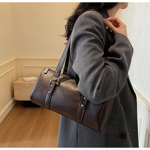 Vue détaillée d'un sac à bandoulière marron foncé avec rivets sur un mannequin femme