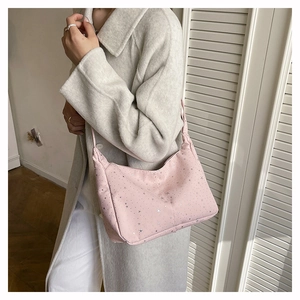 Sac fourre-tout rose en velours avec étoiles argentées porté sur manteau gris