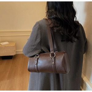 Vue détaillée du sac polochon rétro en cuir marron avec anneaux métalliques argentés clairs