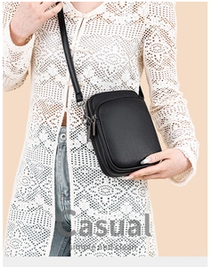 Detail view of black lychee grain leather mini crossbody bag with dual silver zippers