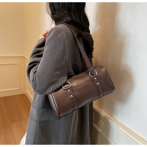Vue détaillée du sac cylindrique marron café avec boucles argentées et texture en cuir