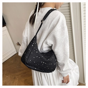 Détail du sac hobo noir à motif d'étoiles porté par un mannequin en intérieur