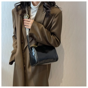 Détail du sac Boston noir brillant avec une large bandoulière tissée géométrique chic