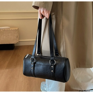 Détail du sac cylindrique en cuir ciré noir avec ferrures argentées et texture lisse