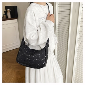 Détail du sac à bandoulière noir avec motifs d'étoiles et de pois blancs sur toile