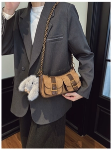 Detail of vintage brown suede shoulder bag with chain strap and plush bunny charm