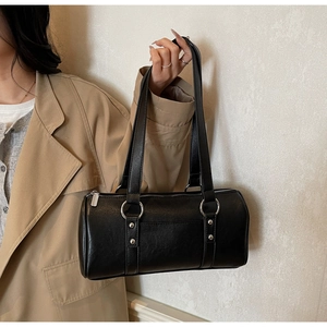 Détail du sac cylindrique noir porté épaule avec anneau argenté et rivets métalliques