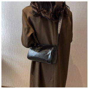 Vue de dos du mannequin portant un sac cylindre noir avec bandoulière jacquard géométrique