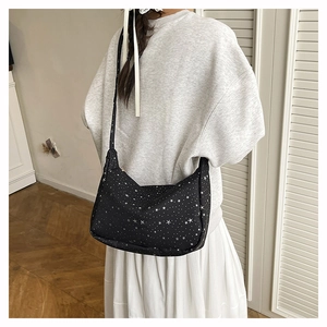 Détail du sac bandoulière noir en croissant avec étoiles et ruban blanc décoratif