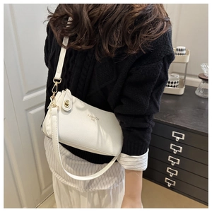 White lychee texture PU crossbody bag with golden clasp and adjustable strap worn by model