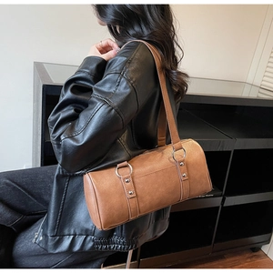 Sac bandoulière cylindrique marron porté par un mannequin montrant le style vintage