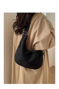Rear view of model wearing black canvas crescent crossbody bag with adjustable wide strap