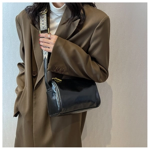 Détail du sac polochon noir brillant avec bandoulière tissée géométrique bicolore