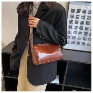 Détail d'un sac oreiller marron avec texture brillante et bandoulière tissée vintage
