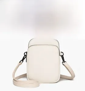 Detail of cream mini crossbody bag showing lychee pattern faux leather and zippers