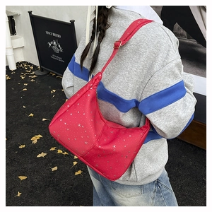 Détail du sac hobo rouge en demi-lune avec étoiles argentées porté par un mannequin dehors