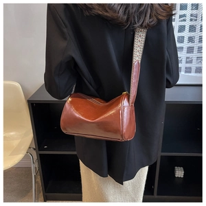 Détail du sac polochon marron foncé avec une bandoulière tissée aux motifs ethniques