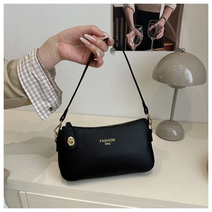 Detail of black litchi grain leather bag featuring gold Fashion Bag text and metal hardware