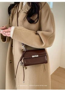 Detail view of brown PU leather shoulder bag with metallic lock and tassel on a model
