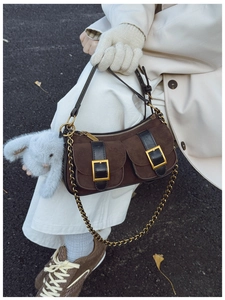 Detail of retro suede shoulder bag with gold buckles and a cute blue bunny pendant