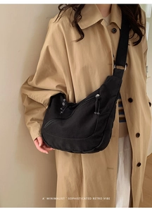 Detail view of a black canvas crossbody bag with adjustable strap and metal buckle