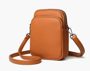 Detail of lychee textured leather and gunmetal hardware on a compact crossbody bag