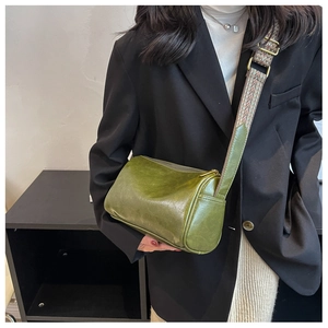 Détail du sac cylindre en cuir vert vintage avec bandoulière tissée géométrique