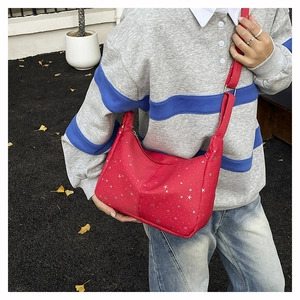 Détail d'un sac demi-lune rouge avec imprimés d'étoiles argentées et bandoulière