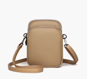 Detail of tan lychee grain leather crossbody bag featuring dual zippers and metal hooks