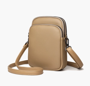 Detail view of khaki mini crossbody bag with triple zippers and lychee grain texture