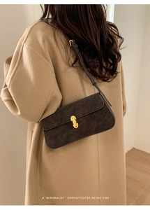 Détail du sac sous le bras en daim marron foncé avec fermoir doré sur manteau camel