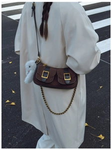 Close-up of retro suede crossbody bag with double pockets and plush rabbit pendant