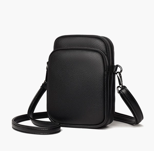 Detail of black pebbled leather crossbody bag with three zipper compartments